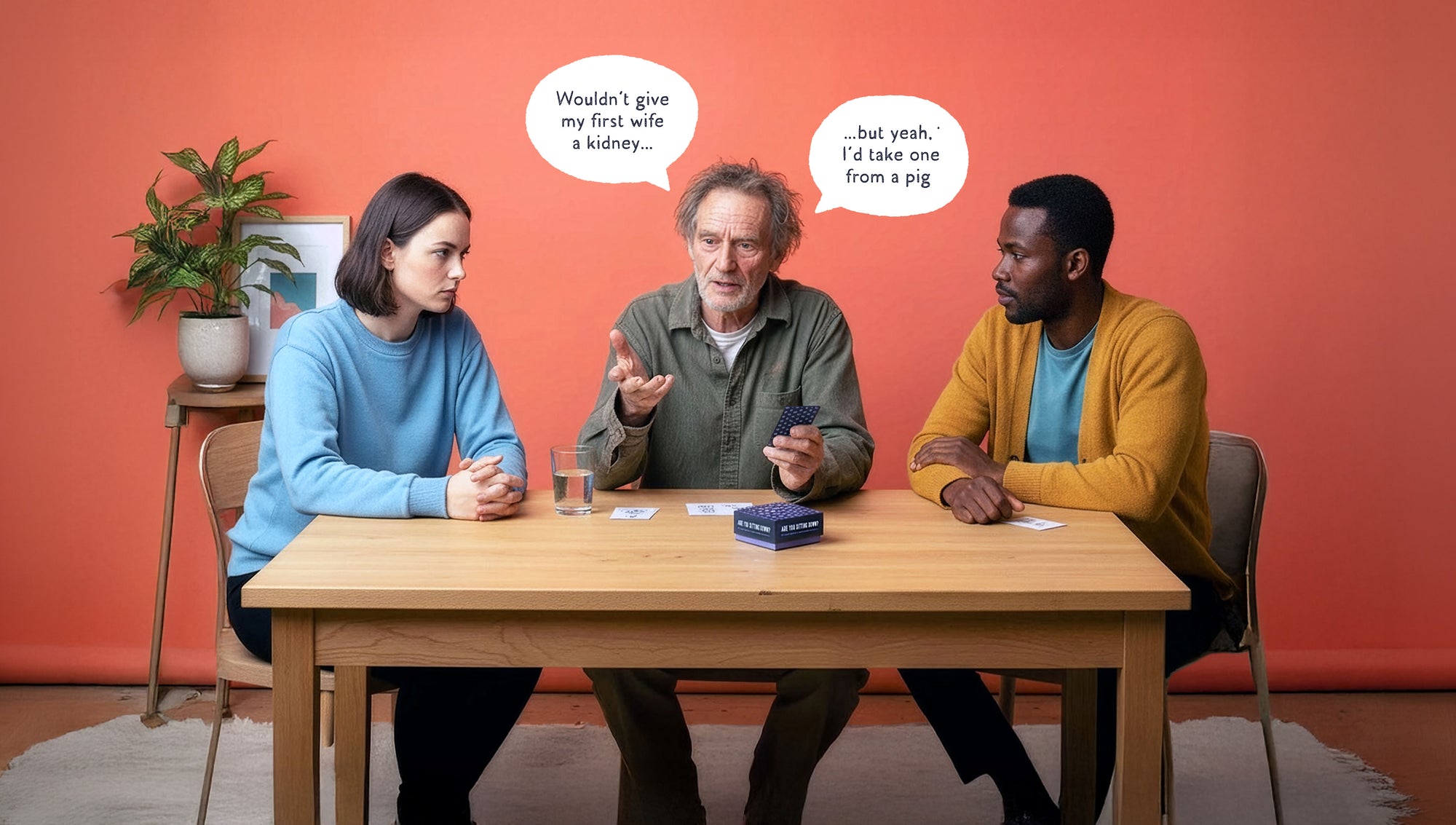 Three people sitting around a table playing Are You Sitting Down? conversation card game, showcasing the unique artwork and thought-provoking questions